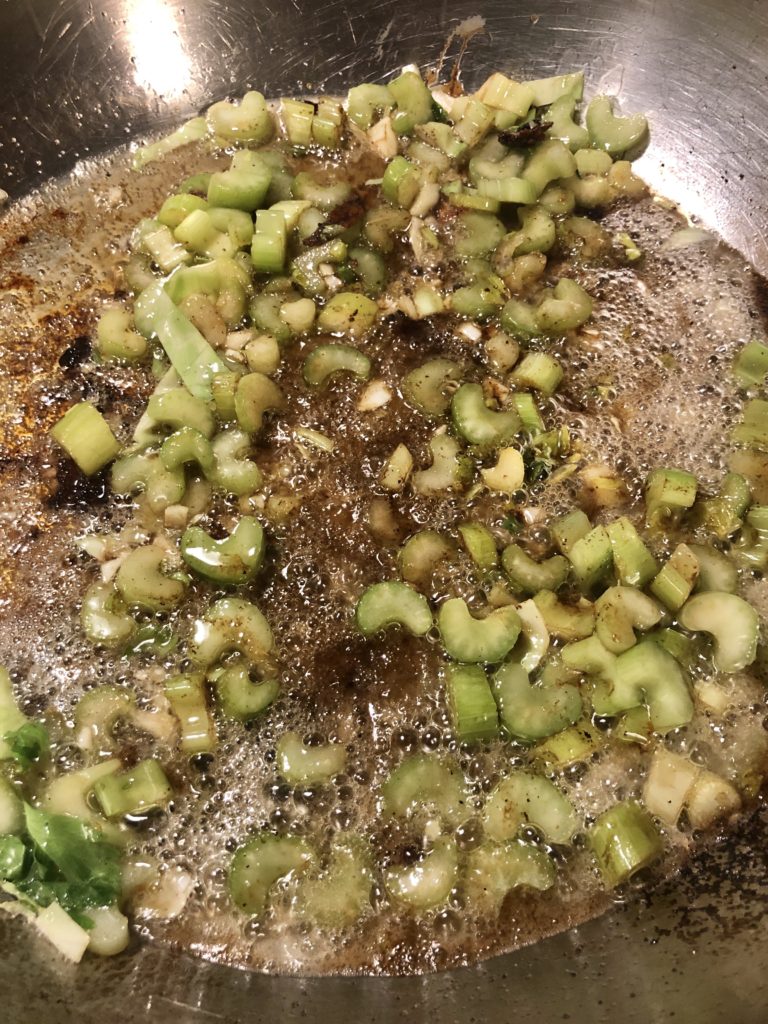 Celery and vegetable oil are frying in a large skillet.