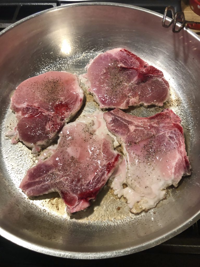 Four pork chops added to large skillet and seasoned with salt and black pepper.