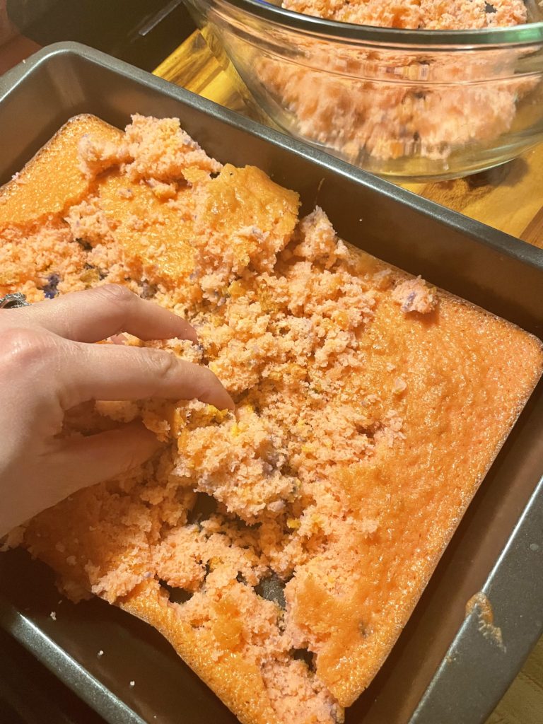 Breaking apart a baked strawberry cake in the baking pan.