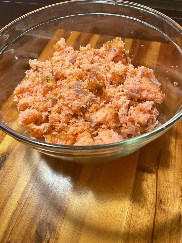 Adding broken apart strawberry cake to a trifle bowl.